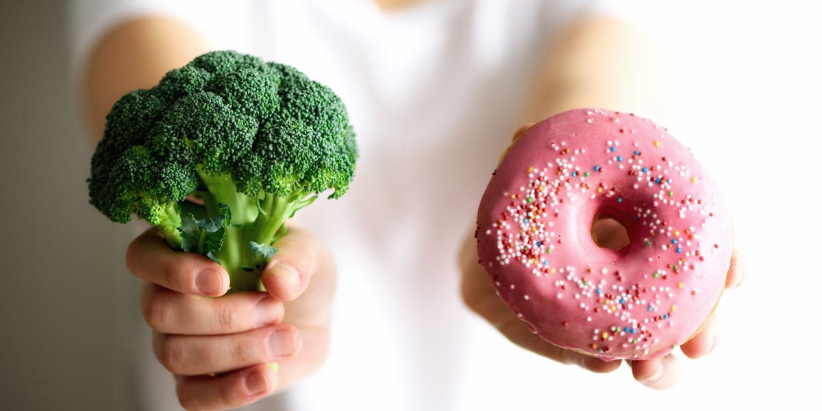 personne tenant un brocoli et un beignet pour illustrer des choix alimentaires sains