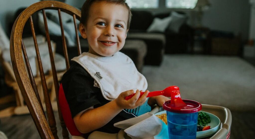 Bambino seduto che mangia su un seggiolone